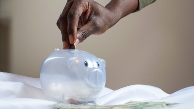 person putting coin in a piggy bank